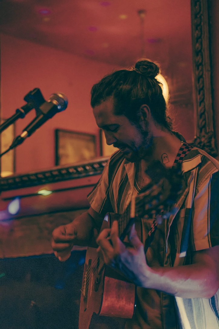 Colin playing guitar on stage under coloured lights