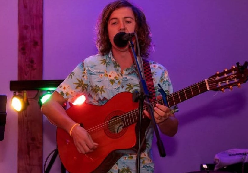 Colin singing and playing acoustic guitar during a live performance